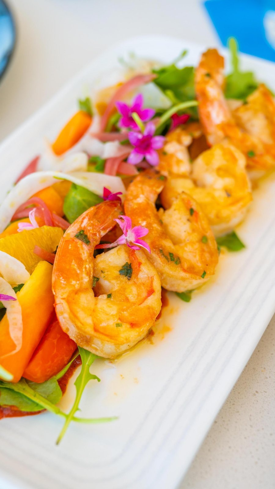 a plate with shrimp atop a salad and garnished with flowers at Ocean Seven at the Hiatus Hotel on Clearwater Beach