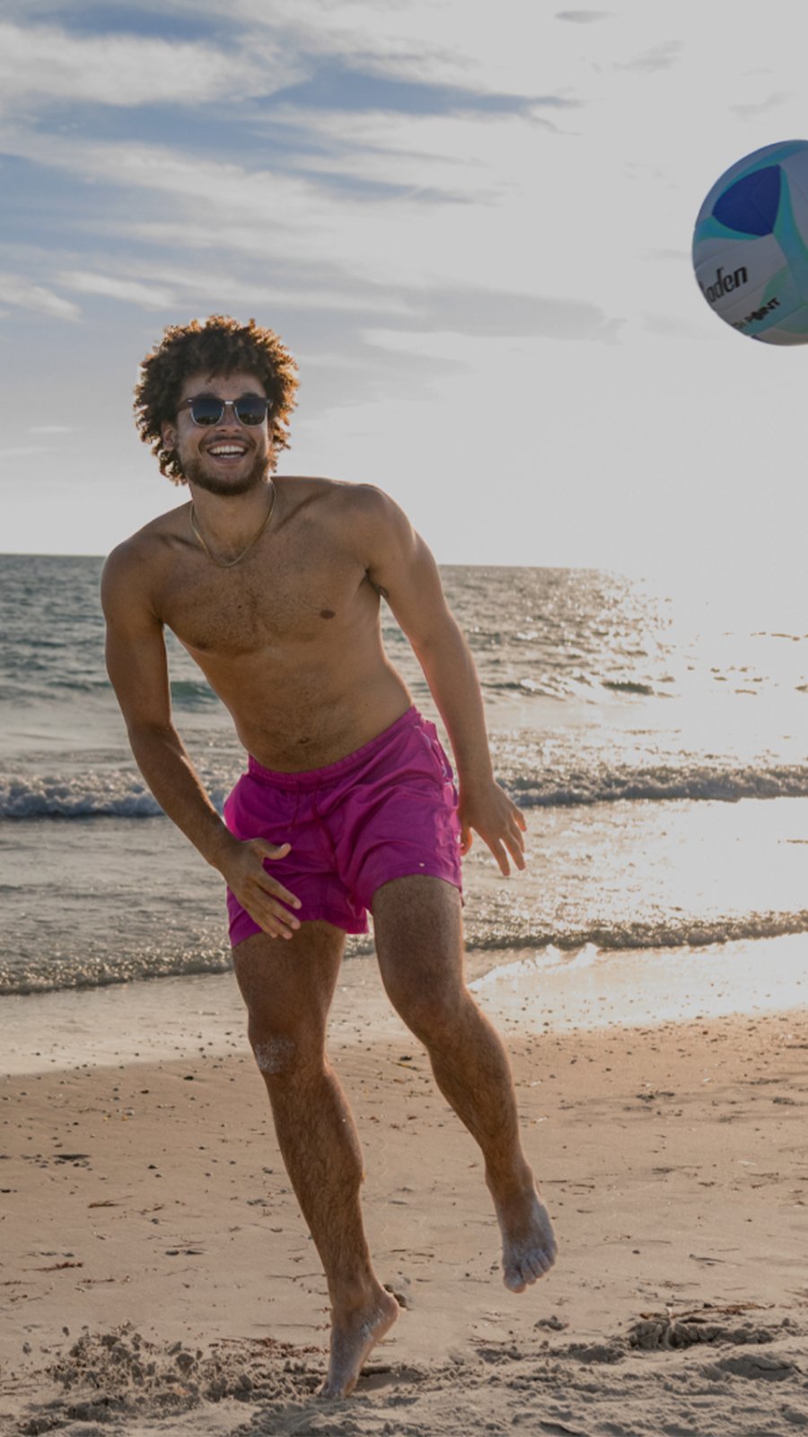 a smiling young man kicking a soccer ball on one of St. Pete-Clearwater's Beaches